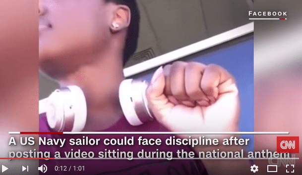 US navy sailor sits down during national anthem